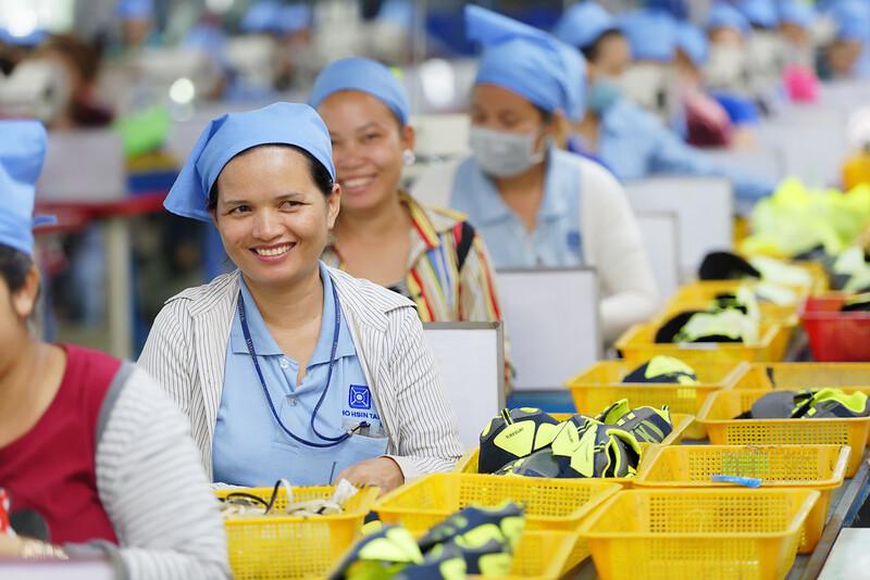 Una trabajadora de una fábrica sonriendo durante su turno en una planta de fabricación de calzado de Camboya.
